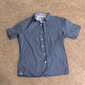 This shirt is a Van Heusen never-tuck it is blue with small roses on it.